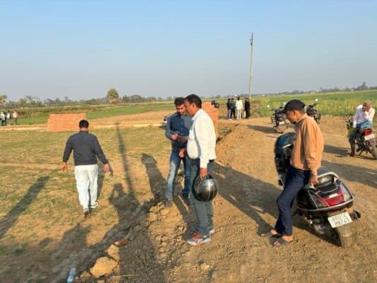 Sprawling open land at Ayansh Homes with prospective buyers analyzing property, showcasing real estate development and investment potential in a serene rural setting.